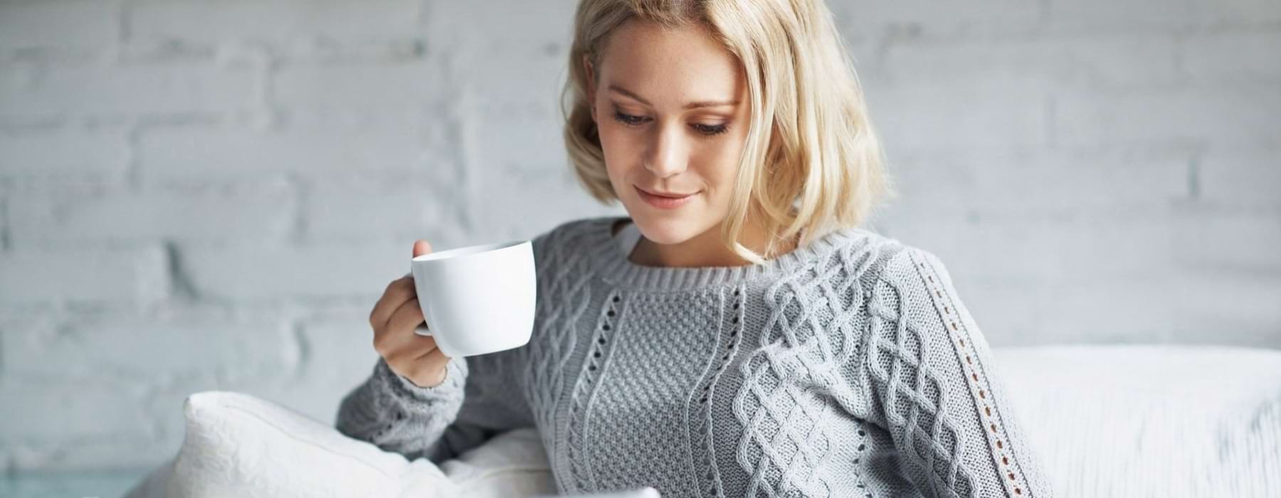 woman drinking coffee and reading a paper
